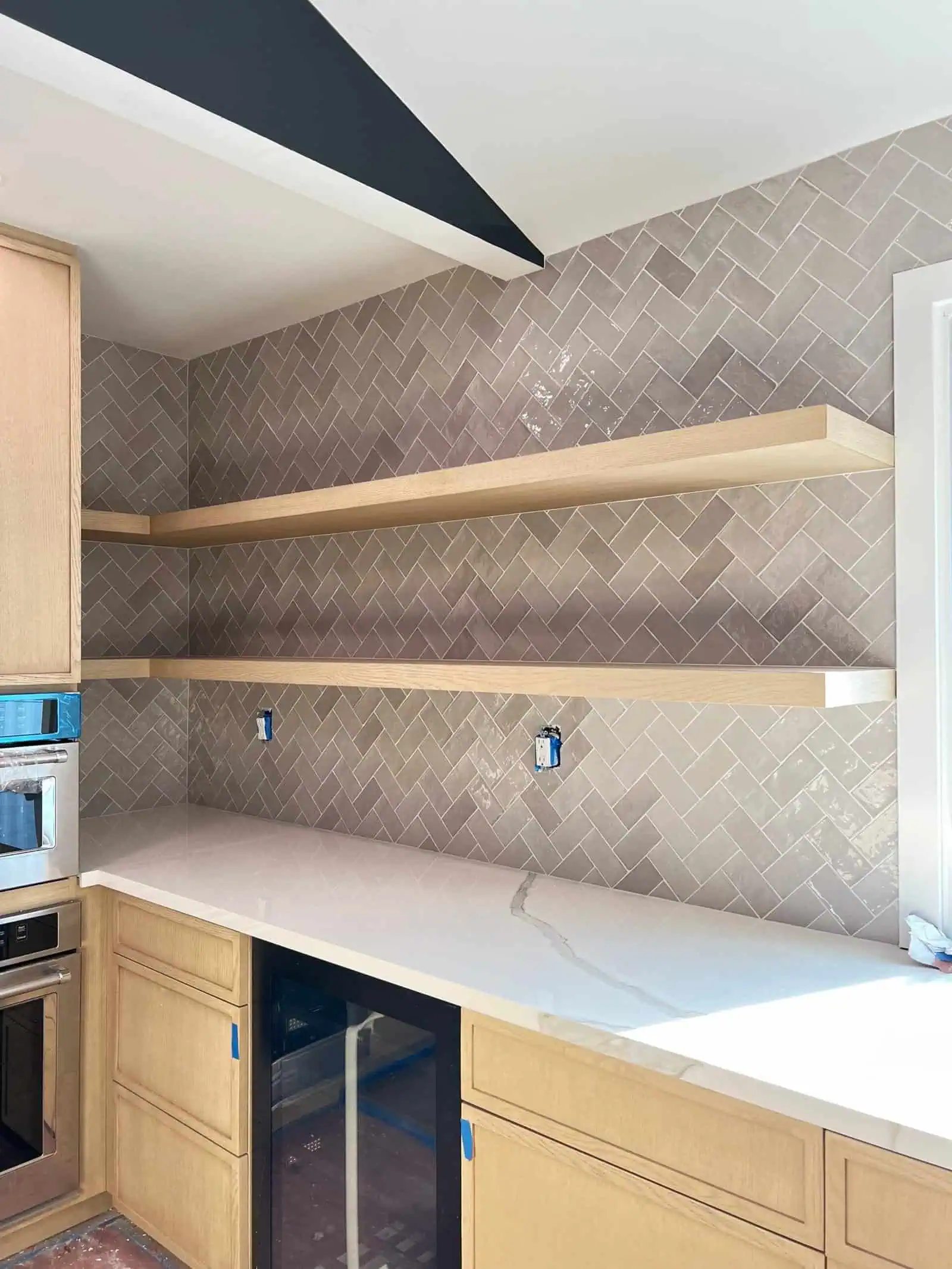 Herringbone tile backsplash with beige and taupe tones in a contemporary kitchen setting.