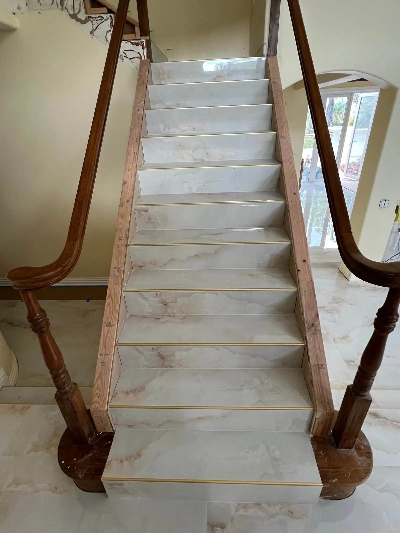 Elegant marble staircase with wooden handrails in a residential interior.